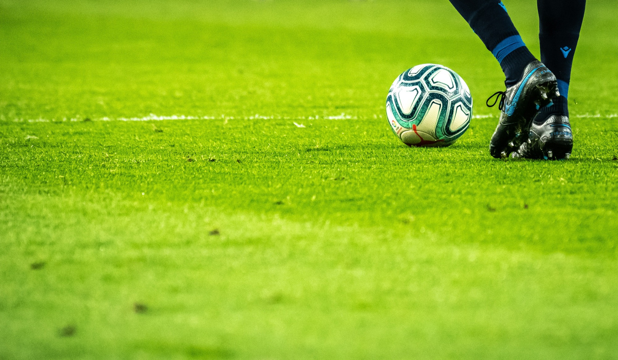Footballer's boot beside the ball on grass