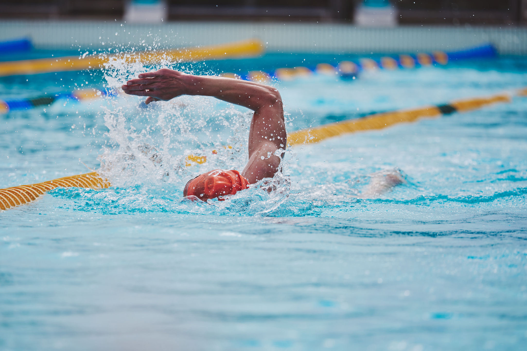 Freestyle swimmer mid-stroke in an outdoor lane